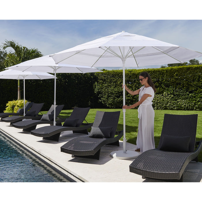 Woman adjusting a large white Helux market umbrella near lounge chairs by a pool