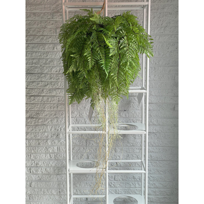 A lush fern drapes over a white ladder against a brick-textured wall.