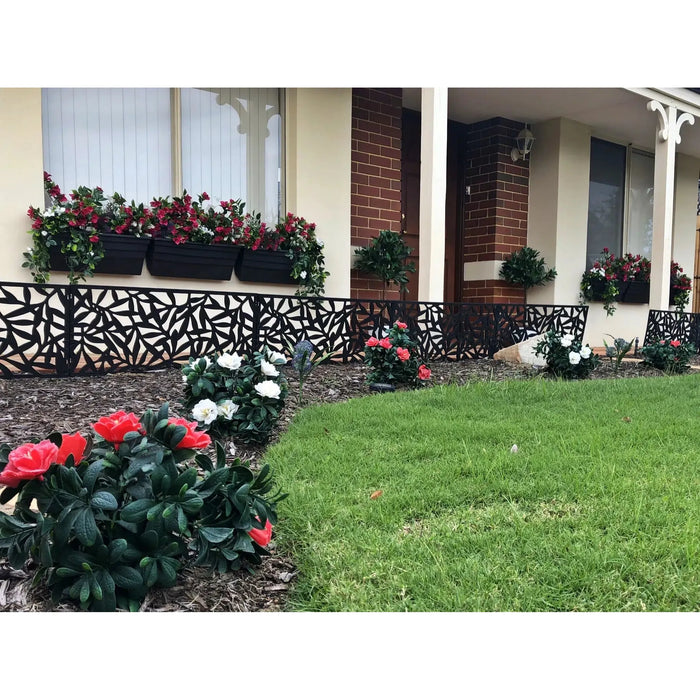 A house with a (5 Pieces) Vibrant Pink Hanging Artificial Bougainvillea Plant, UV Resistant 35" in a flower bed in front of it.