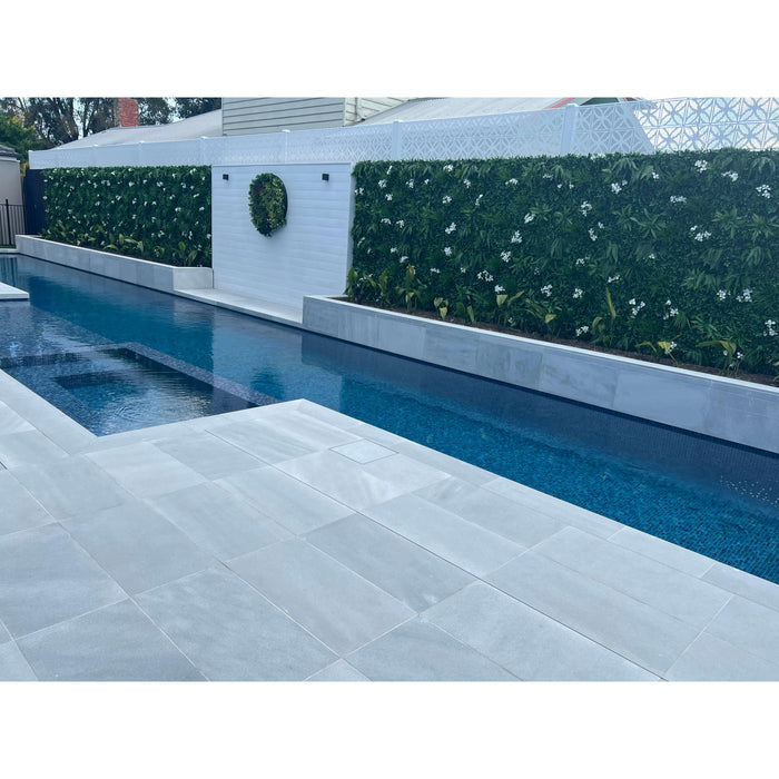 Premium artificial green wall with flowers next to a pool