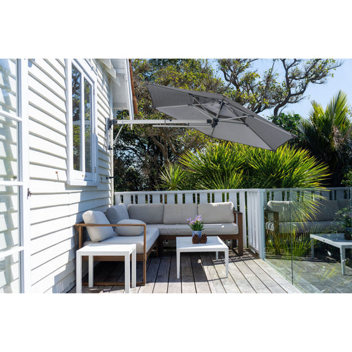 Shadowspec Retreat Wall Mounted Umbrella at a tilted angle providing shade over a patio sectional.