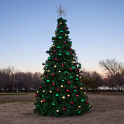 20 foot Decorated Christmas tree with colorful ornaments in an open field at dusk.
