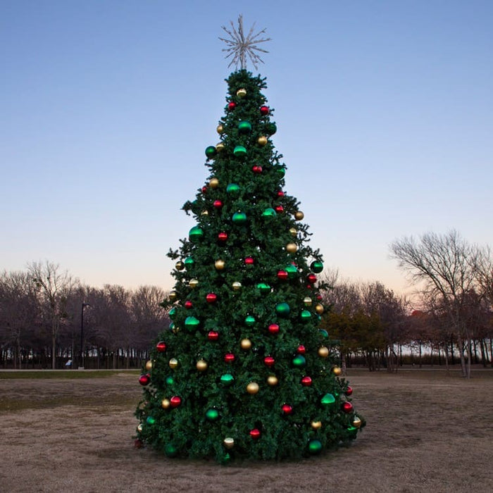20 foot Decorated Christmas tree with colorful ornaments in an open field at dusk.