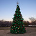 20 foot Decorated Christmas tree with colorful ornaments in an open field at dusk.