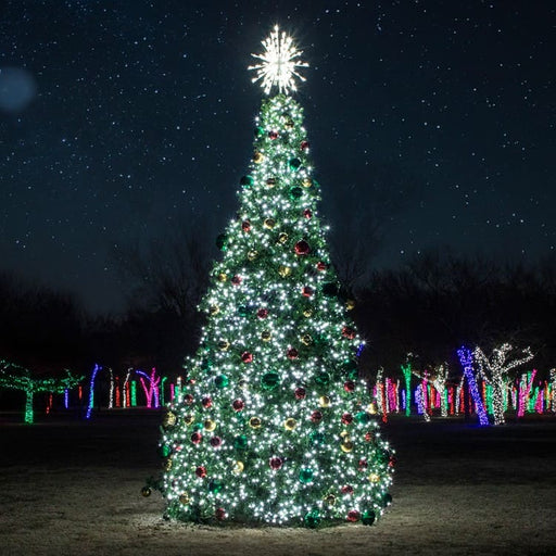 32 foot Decorated Christmas tree with lights and ornaments against a dark sky with star-like lights.
