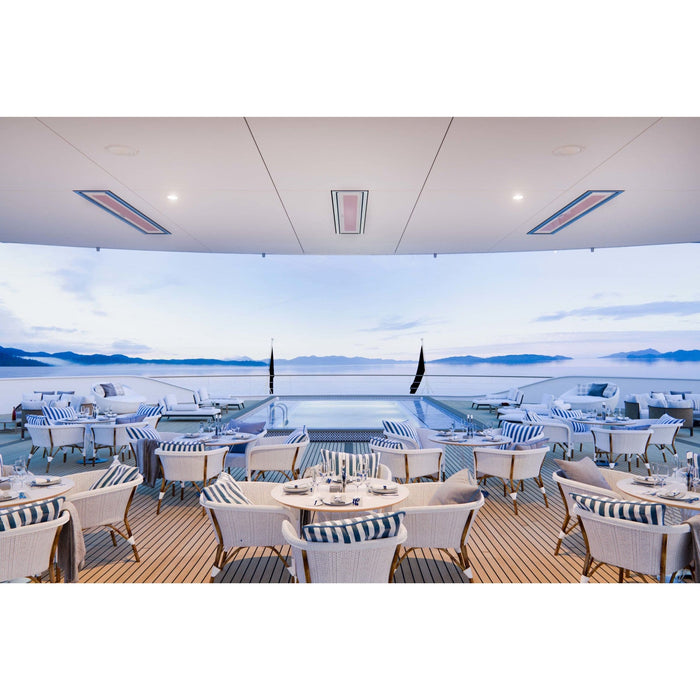 Outdoor dining area on a boat with tables and chairs under a clear sky.