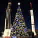 40 ft Decorated Commercial Christmas tree with two rocket models on either side at night.