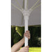 Person adjusting a white outdoor Helux market umbrella with a blurred green background
