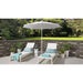 Two white lounge chairs with blue cushions under a large white Helux umbrella on a patio.