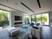 Modern living room with a fireplace, TV, and large windows.