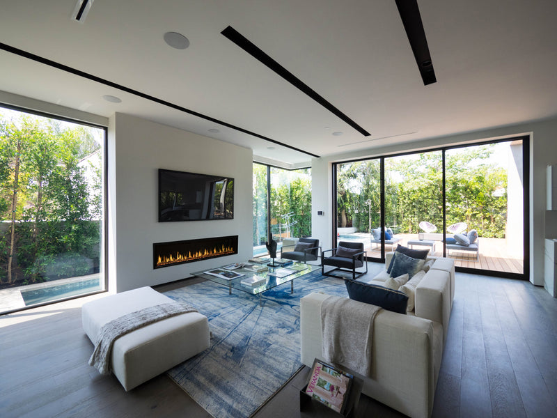 Modern living room with a fireplace, TV, and large windows.