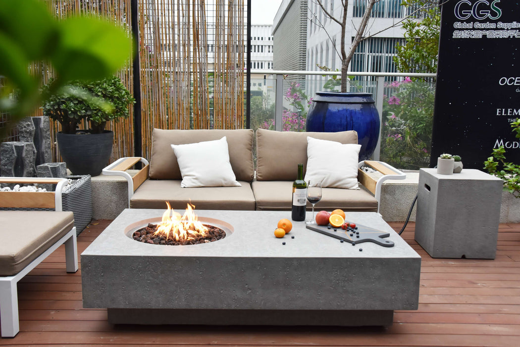 Outdoor patio setting with a Elementi Metropolis fire pit table, sofa, and decorative elements.