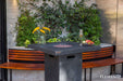 Outdoor Elementi Montreal patio fire table with benches and decorative elements against a wall with greenery