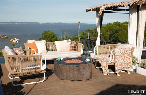 Outdoor patio with wicker furniture, Columbia fire pit by Elementi, and scenic view of water and trees.