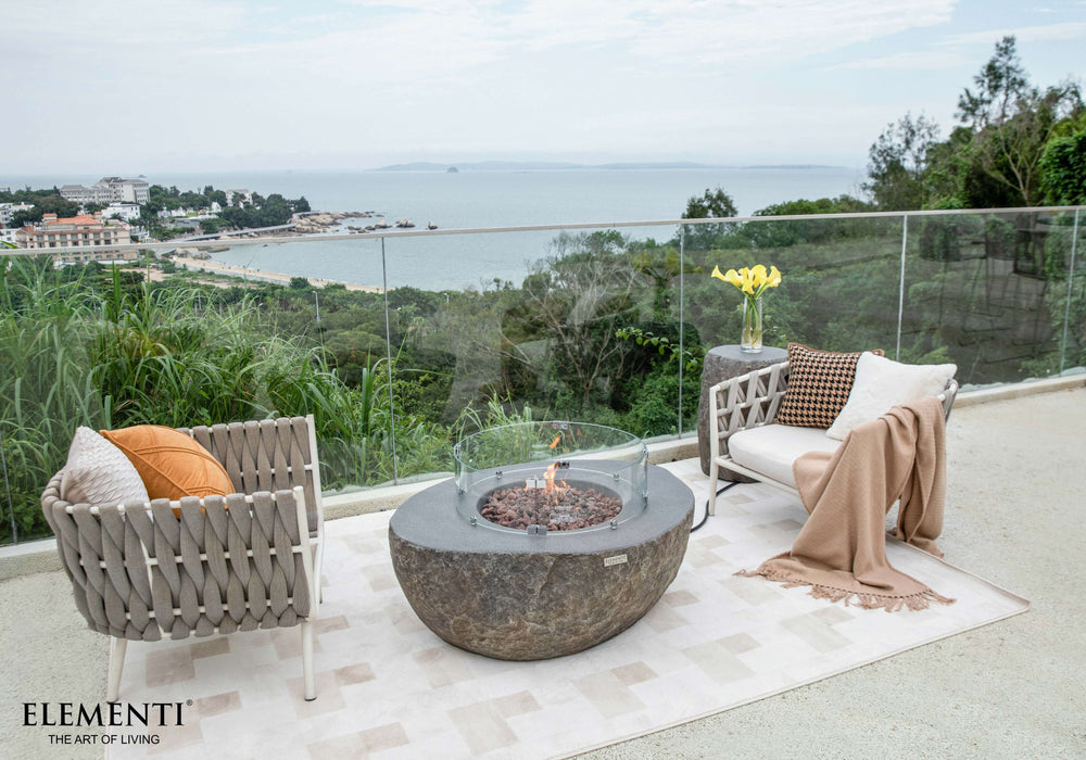 Outdoor patio with fire pit, chairs, and a scenic view of water and trees.