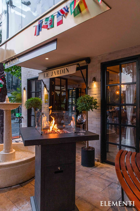 Outdoor Elementi Montreal fireplace in front of a building with 'Le Jardin' sign and colorful flags.
