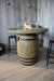 Elementi Lafite Wooden barrel table with a fire pit on top in a room with wooden walls and stools.