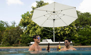 Two men relaxing with beers in a swimming pool under the shade of a white octagonal cantilever outdoor umbrella