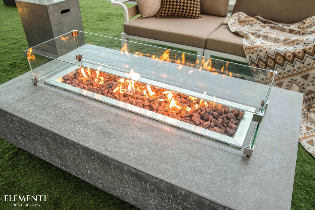 Outdoor Elementi fire pit table with flames on a patio, featuring 'Elementi' branding.