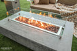 Outdoor Elementi fire pit table with flames on a patio, featuring 'Elementi' branding.