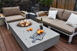 Outdoor patio setup with Elementi Metropolis fire pit table, seating area, and outdoor decor.