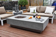Outdoor patio setting with a Elementi Metropolis Fire table, furniture, and decorative items on a wooden deck.