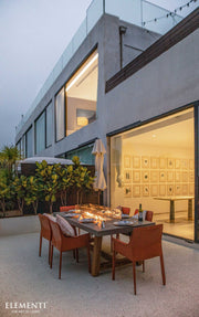 Modern outdoor dining area with fire pit table in front of a house.