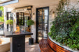 Outdoor seating area with a Elementi Montreal fire pit and 'Le Jardin' sign in front of a building.