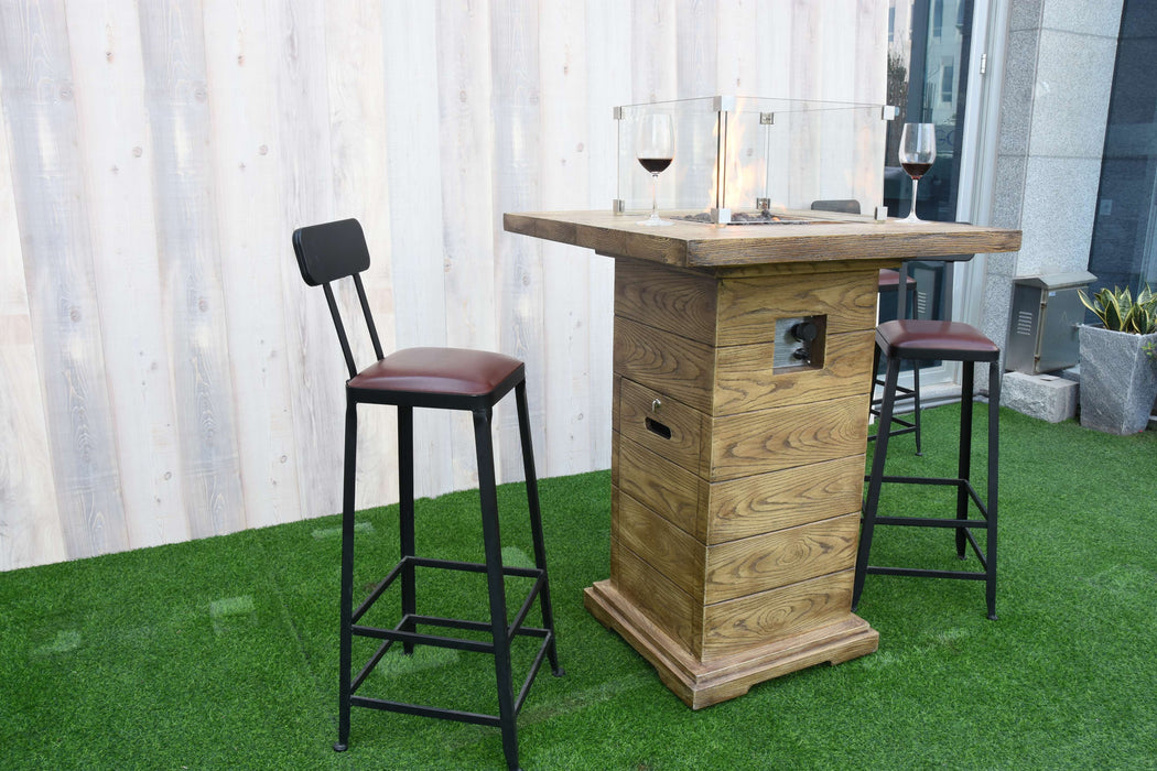 Wooden Elementi Rova bar height table with two stools on a green surface, against a white curtain background.
