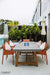 Outdoor dining setup with an Elementi Sonoma table and chairs near a pool area, featuring the Elementi brand.