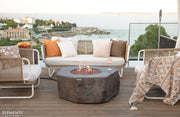 Outdoor patio setting with Elementi Columbia fire pit, chairs, and a scenic view.
