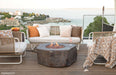 Outdoor patio setting with Elementi Columbia fire pit, chairs, and a scenic view.