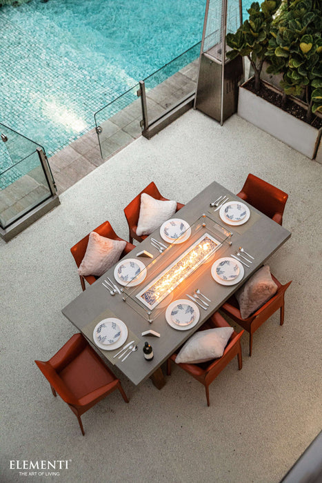 Outdoor Elementi Sonoma dining table with chairs by a pool, featuring Elementi branding.