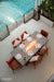 Outdoor Elementi Sonoma dining table with chairs by a pool, featuring Elementi branding.