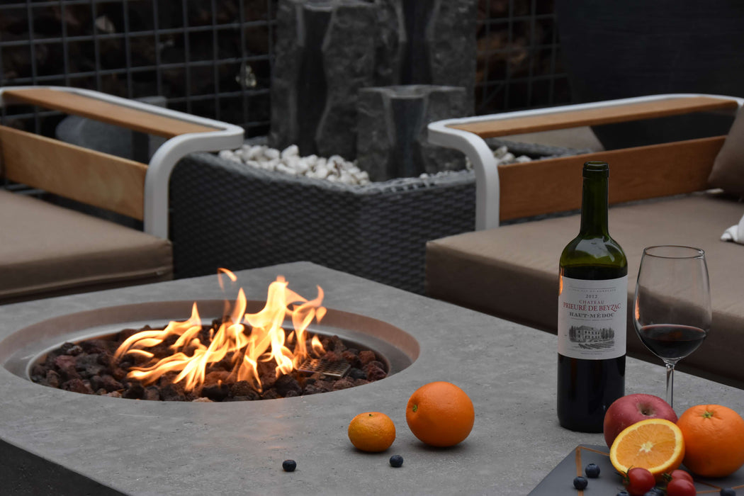 Outdoor setting with a fire pit, wine bottle, and fruit on a patio.