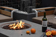 Outdoor setting with a fire pit, wine bottle, and fruit on a patio.