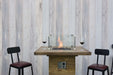 Wooden Elementi Rova table with built-in fire pit and chairs against a wooden paneled wall.