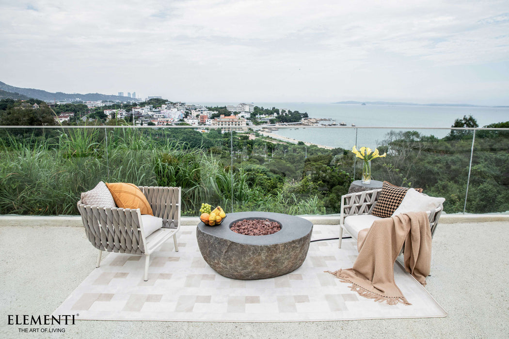 Outdoor patio with fire pit, chairs, and a scenic view of a coastal town.