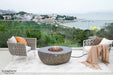 Outdoor seating area with fire pit table and chairs overlooking a scenic view.