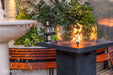Outdoor setting with a Elementi Montreal fire pit table, benches, and a bottle of wine.