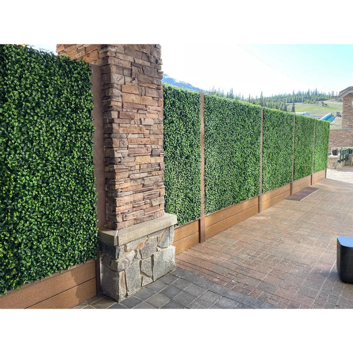 Close-up view of artificial plant wall panels next to a stone pillar.