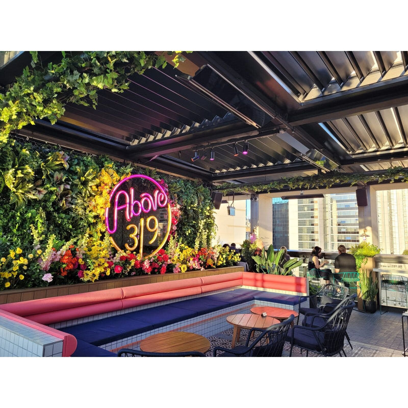Outdoor rooftop bar with neon sign 'Above 319', colorful seating, and urban skyline.