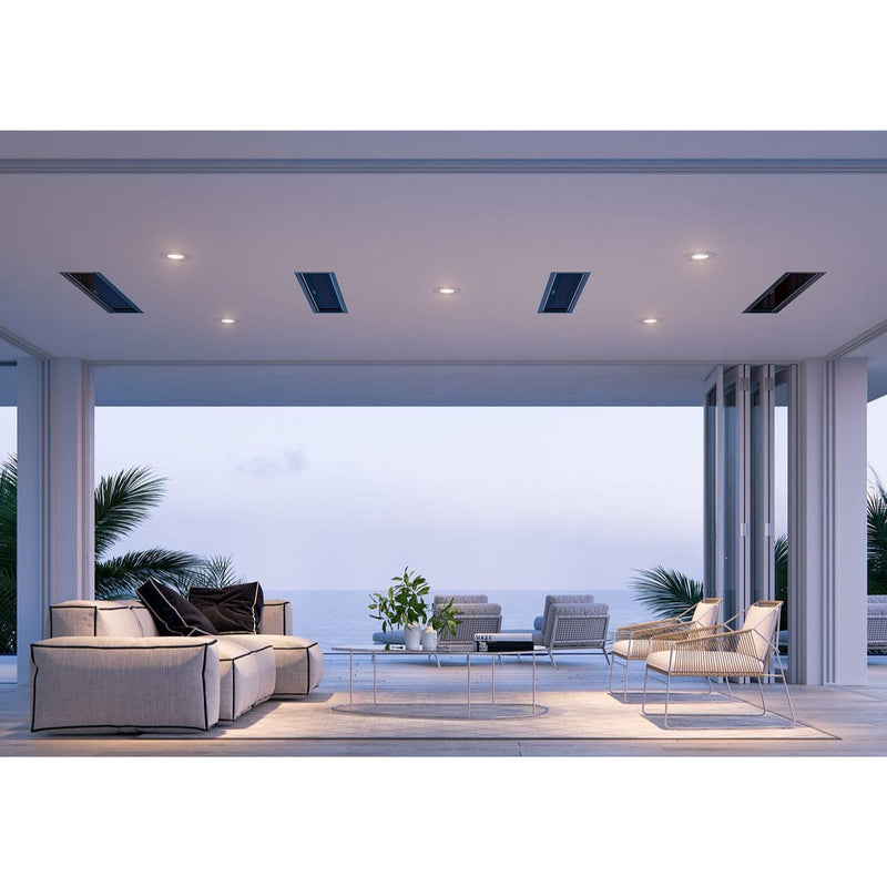 Modern outdoor living space with furniture and a view of the ocean. Four of the Bromic Marine Platinum Heaters in black are seen flush mounted into the ceiling