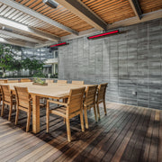 Wooden dining table and chairs on a deck with wall-mounted Bromic heaters.