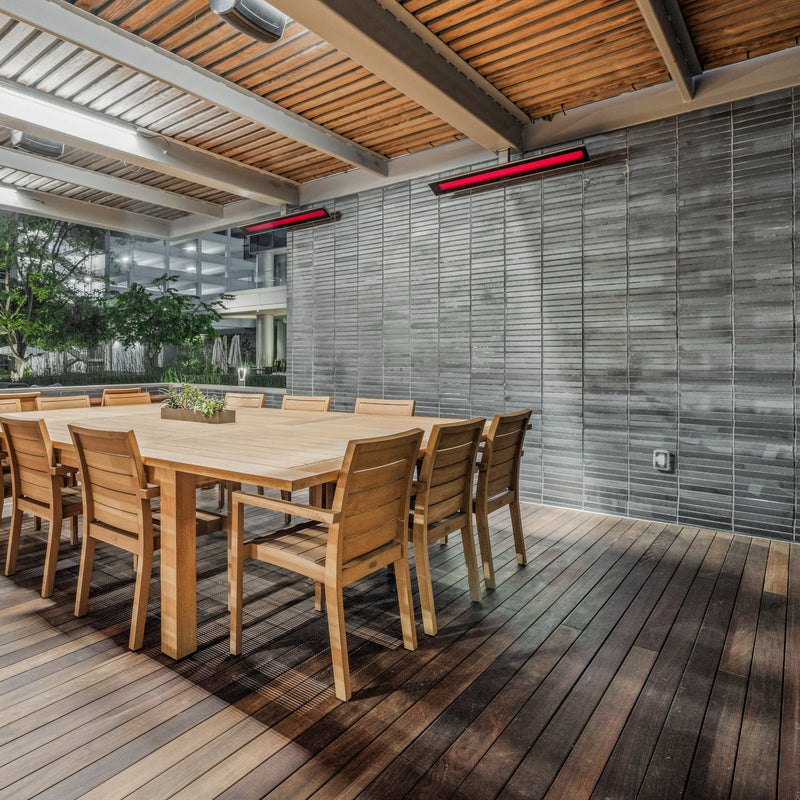Wooden dining table and chairs on a deck with wall-mounted Bromic heaters.
