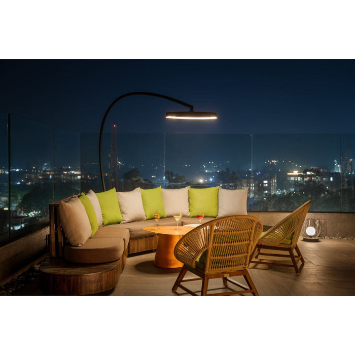 Outdoor evening setting with a couch, chairs, Bromic Eclipse Portable patio heater and table on a rooftop with city lights in the background