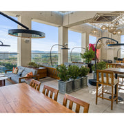 Modern indoor setting with tables, chairs, Bromic Eclipse Portable heaters and large square openings overlooking a cityscape.