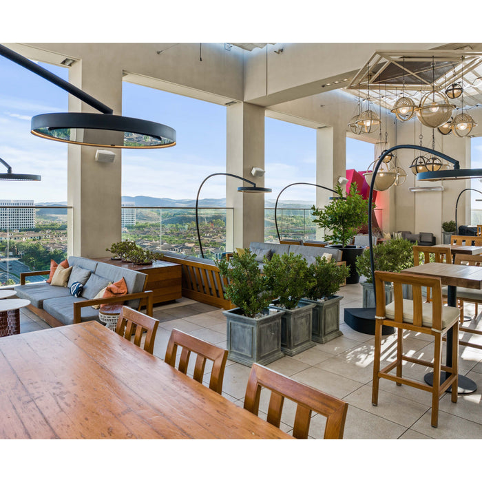 Modern indoor setting with tables, chairs, Bromic Eclipse Portable heaters and large square openings overlooking a cityscape.