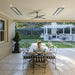 Outdoor patio with a dining table and striped chairs, featuring a ceiling fan, two white Bromic Heaters and potted plants.