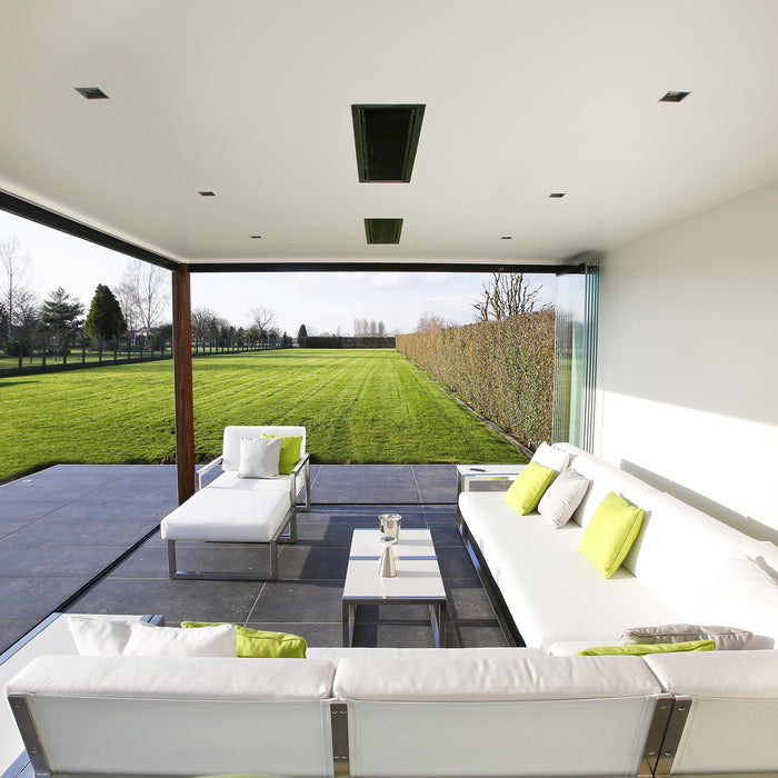 Modern outdoor living space with white sofas and green cushions on a patio with recessed Platinum Heaters by Bromic
